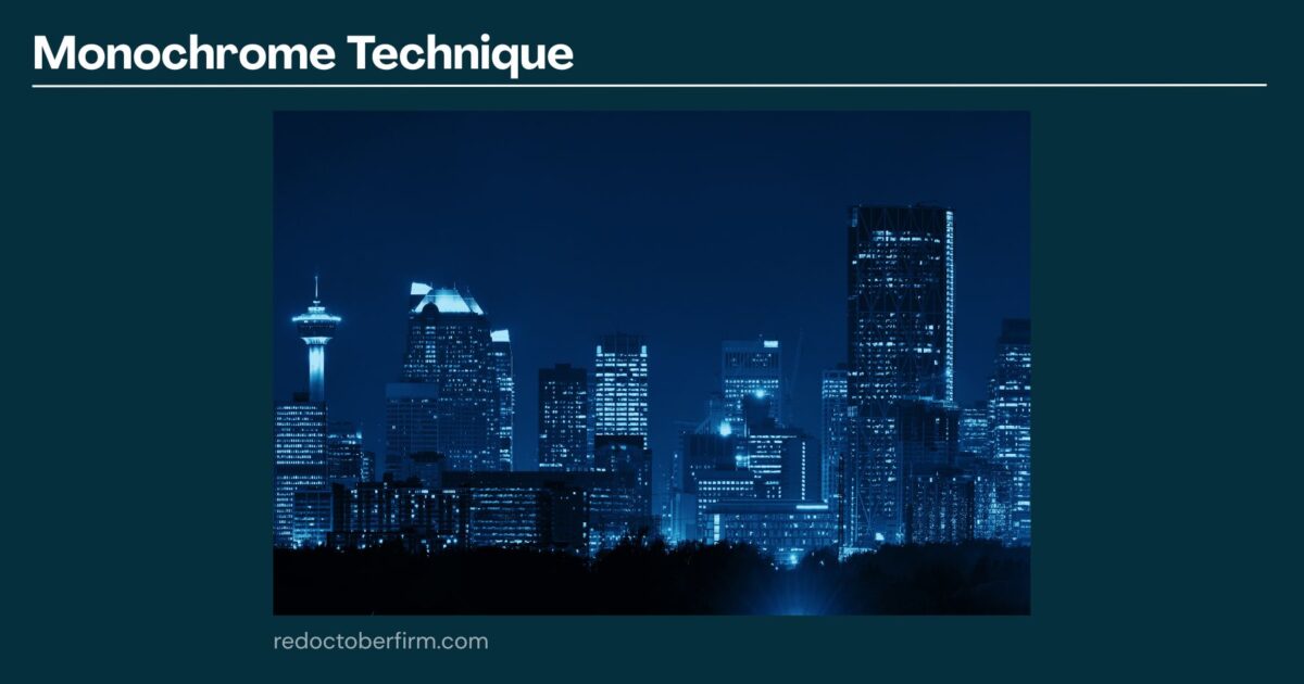22 Basic Photography Techniques You Need To Level Up! A City Skyline At Night Shown In Blue Monochrome, With Various Illuminated Buildings And A Dark Sky Above. The Text &Quot;Monochrome Technique&Quot; Appears At The Top.