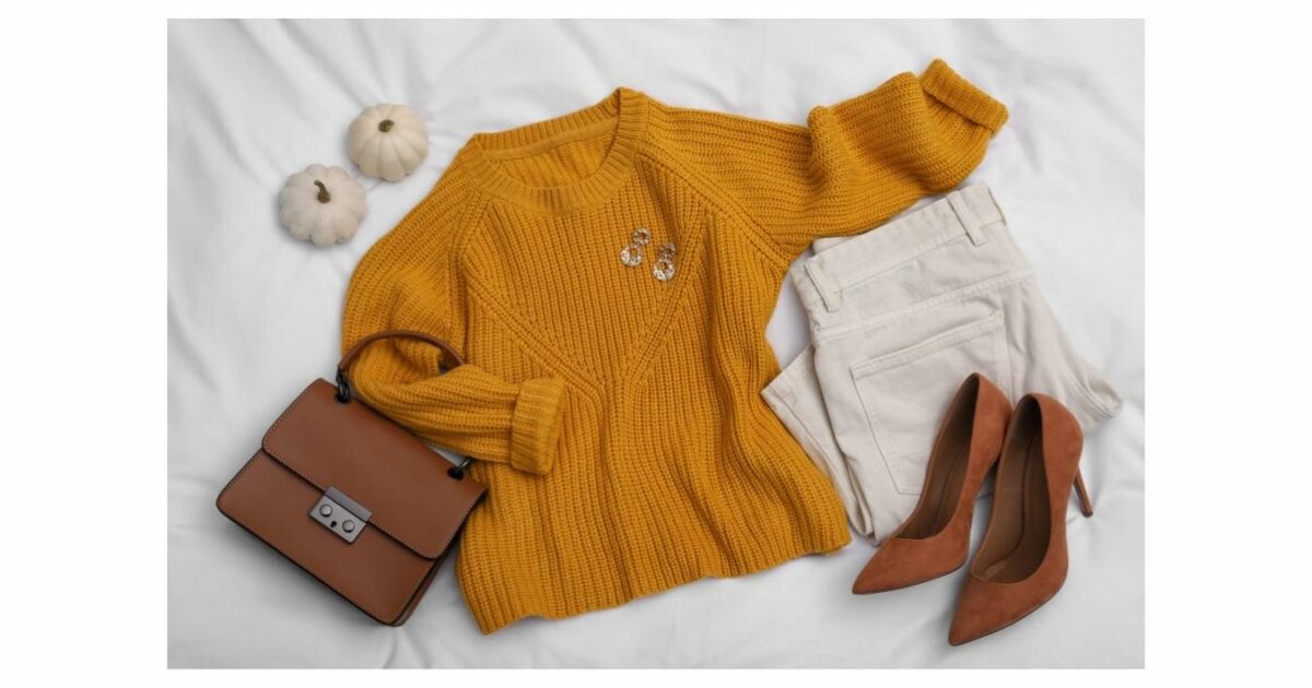 What To Wear To A Photoshoot (The Ultimate Guide) A Yellow Sweater, White Pants And A Purse On A Bed, Showcasing An Ideal Outfit For A Photoshoot.