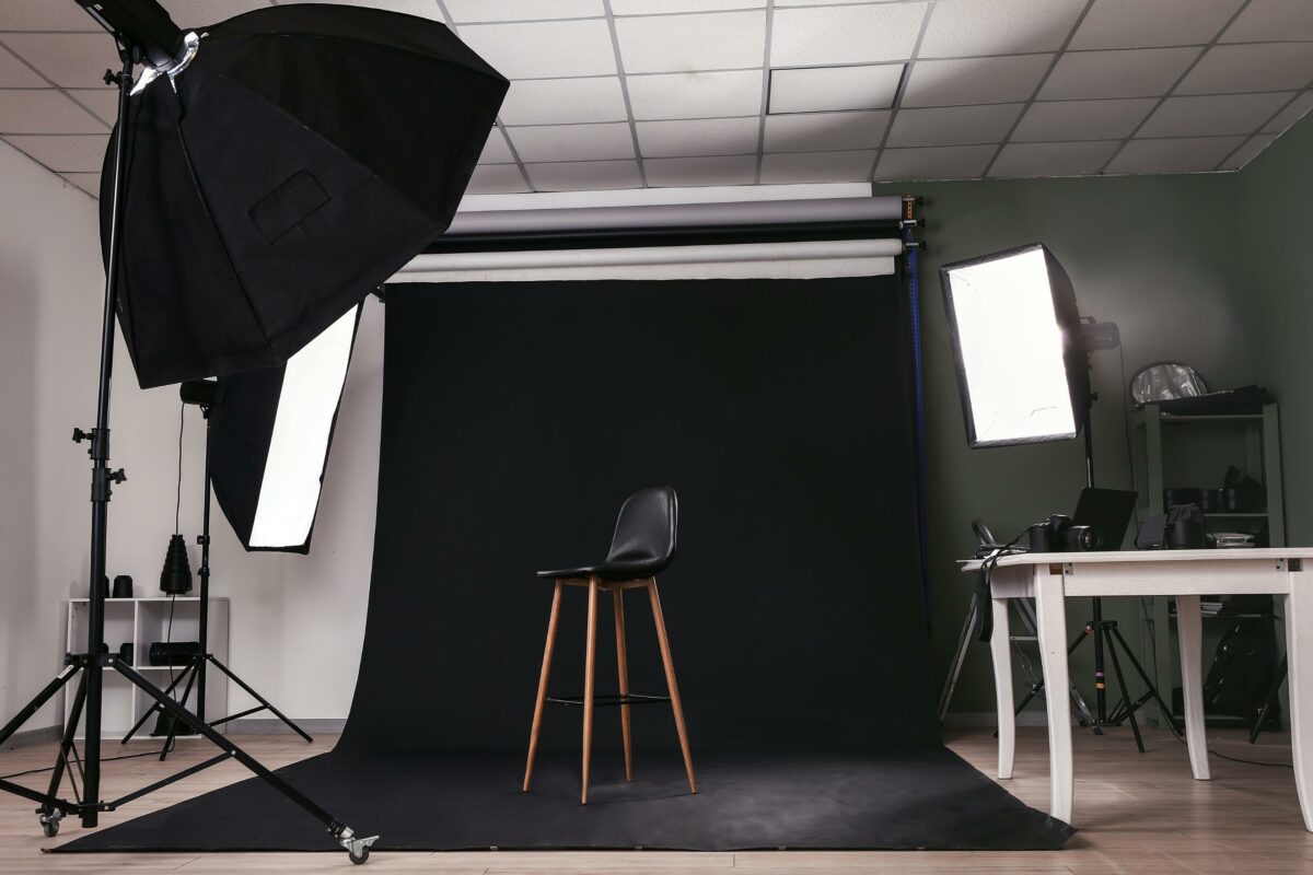 Simple Lighting Techniques For Stunning Photographs A Photo Studio With A Modern Black Background And A Sleek Black Chair, Showcasing Expert Lighting Techniques.