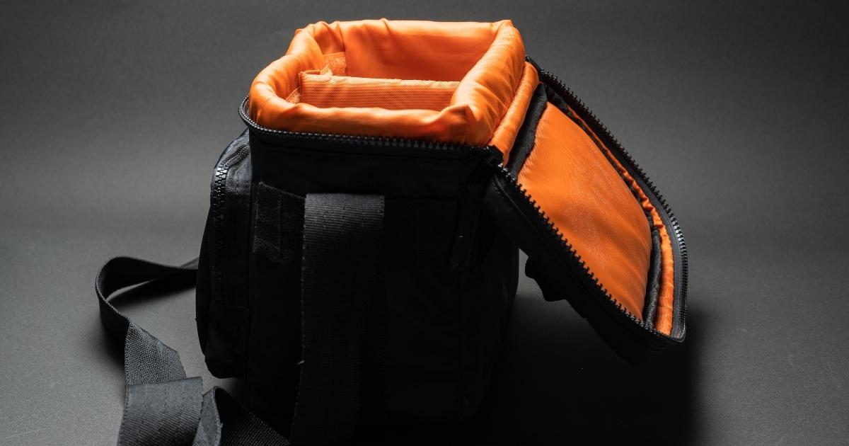 What Is Photography: An Introduction And Quick Guide A Camera Bag With Orange And Black Design Placed On A Black Surface, Representing Photography.
