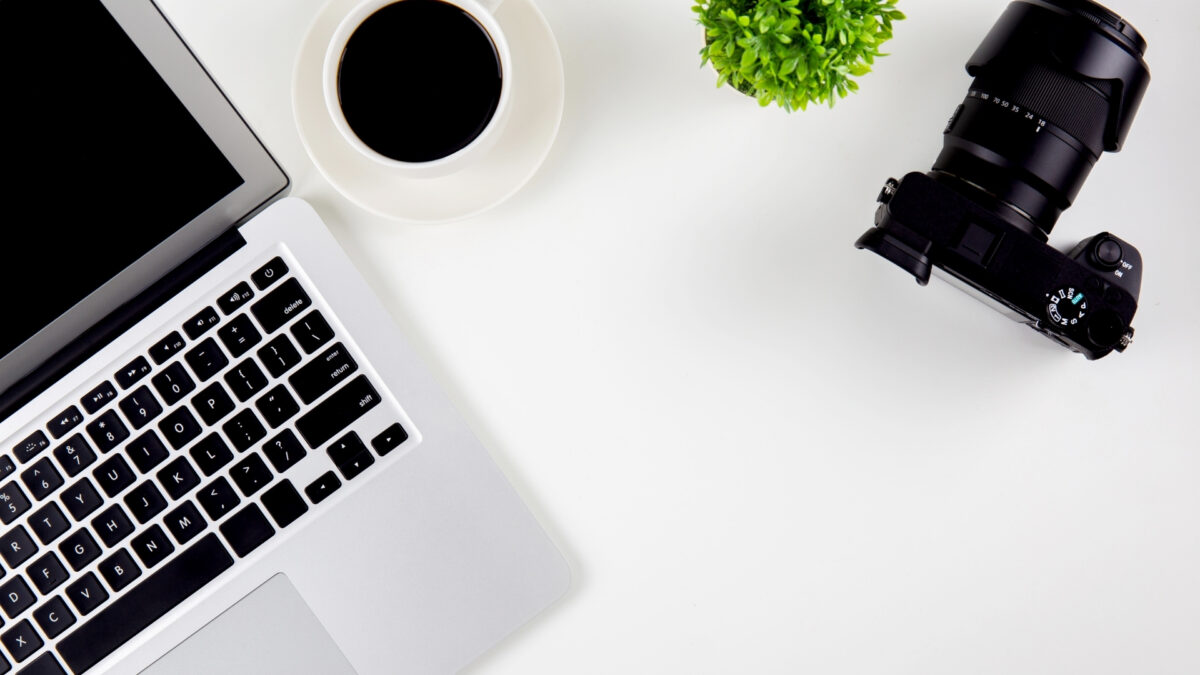 How To Store And Backup Photos Safely A Laptop With A Camera On A White Table, Perfect For Storing And Backing Up Photos.