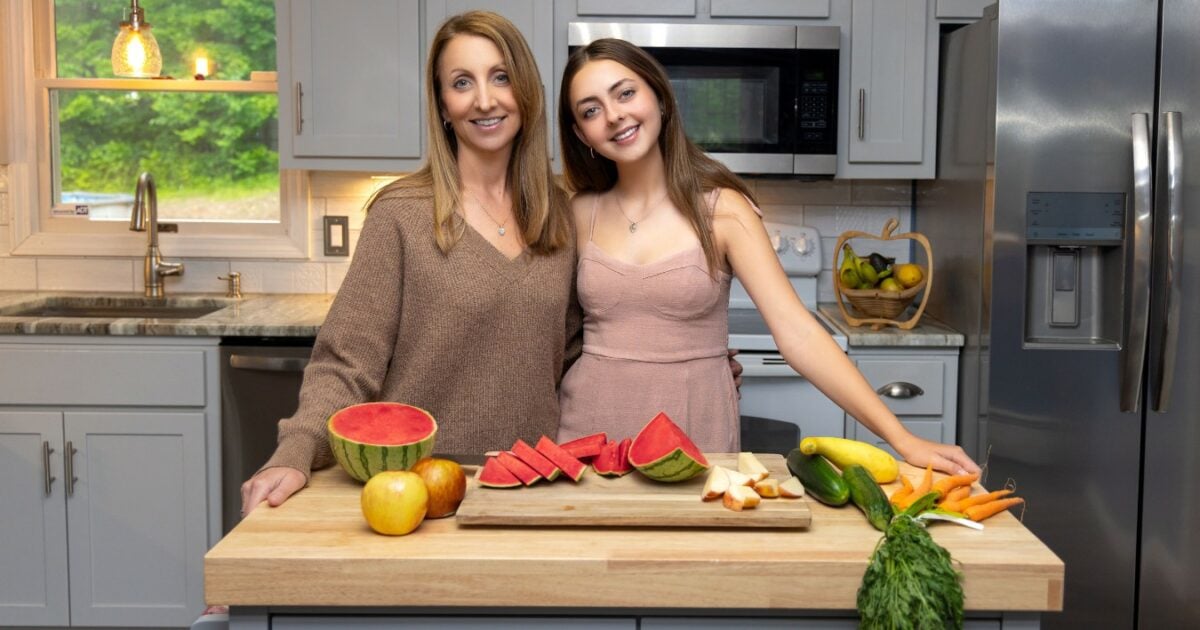 Best Photography Poses For Pictures (From A Pro Photographer) Two Women Posing In Front Of A Cutting Board With Fruits And Vegetables For Pictures.