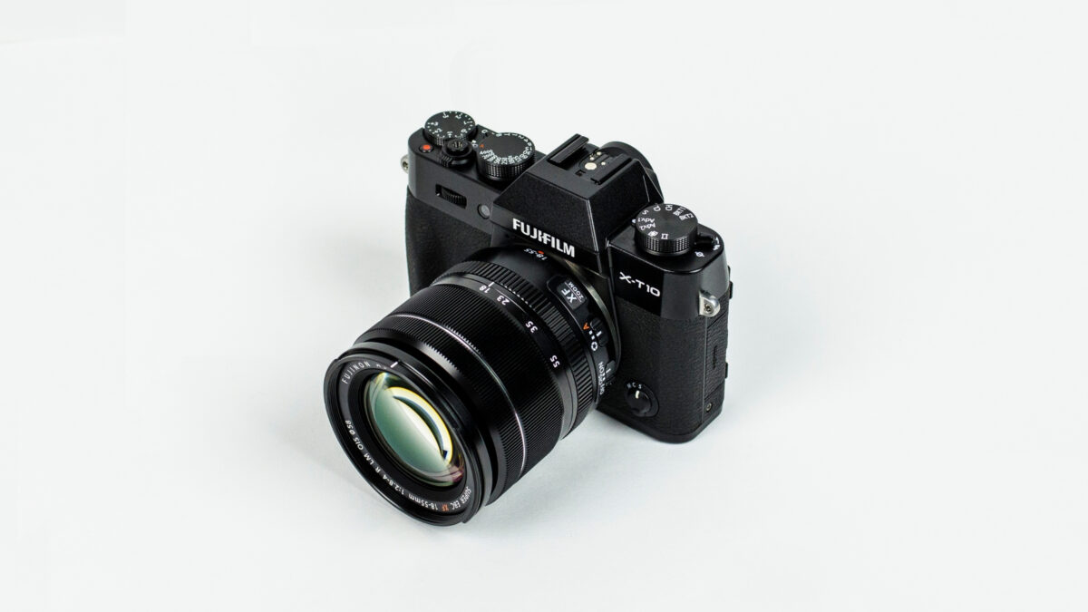 Dslr Vs. Mirrorless (What'S Best For A New Photographer?) A Black Camera (Dslr) On A White Background.