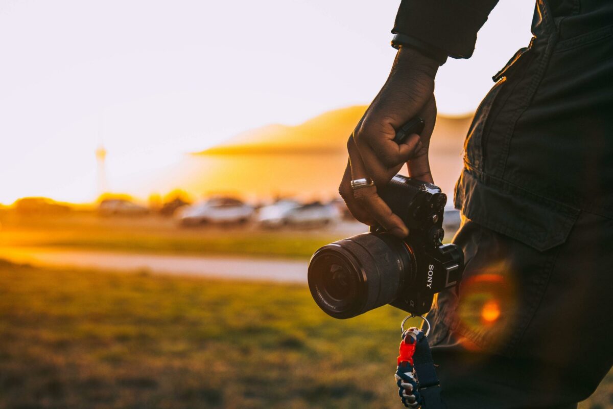 12 Mistakes Photographers Make A Person Holding A Camera At Sunset.