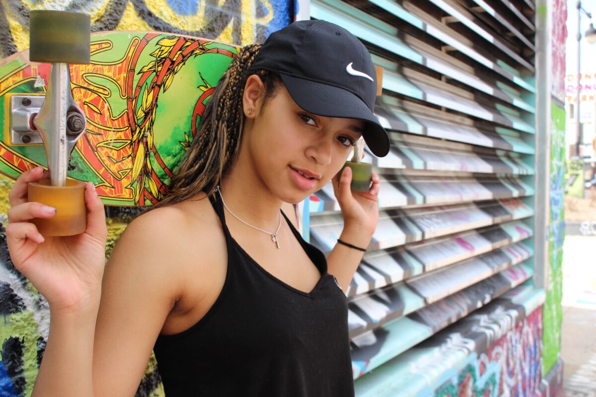 Photography For Beginners (How To Take Pictures Like A Pro) A Woman Holding A Skateboard In Front Of A Graffiti Wall, Suitable For Photography Beginners.
