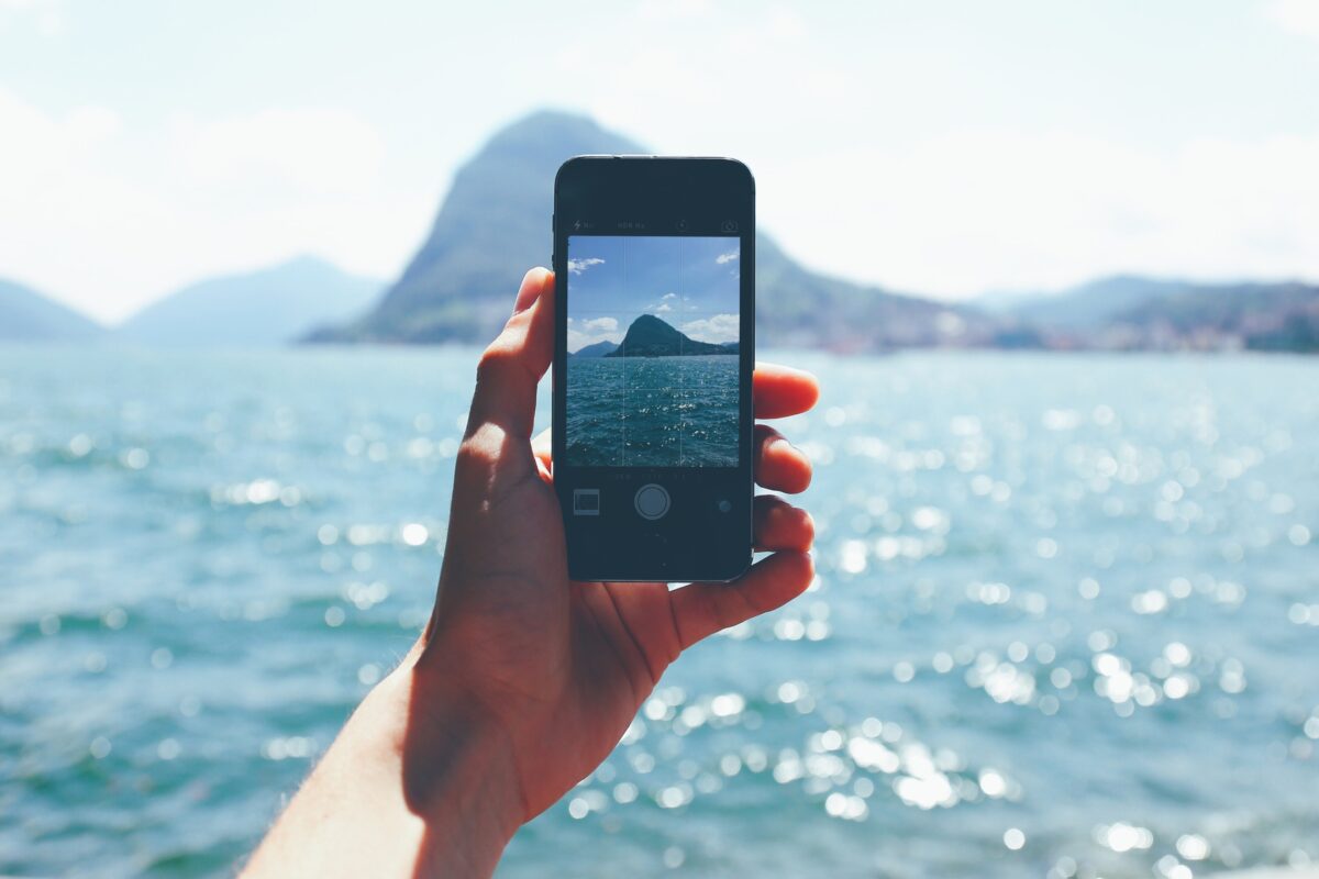 Mobile Photography Tips That'Ll Help You Take Better Photos A Person Capturing The Beauty Of The Ocean With A Cell Phone Using Mobile Photography.