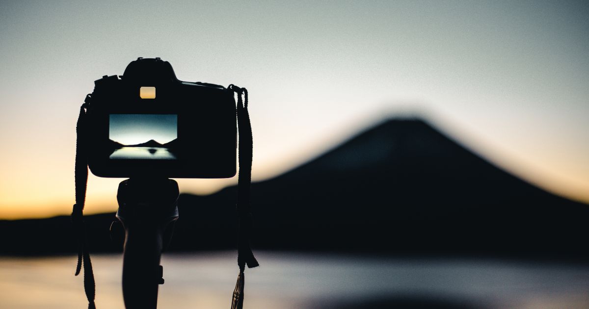 Photography For Beginners (How To Take Pictures Like A Pro) A Photo Of A Camera With A Mountain In The Background, Perfect For Beginners In Photography.
