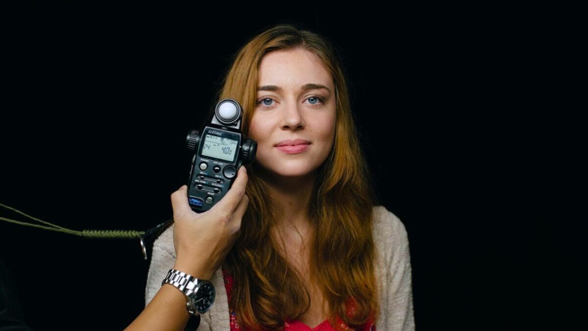 Photography Lighting Tips For Taking Better Photos A Woman Is Holding A Cell Phone In Front Of A Black Background, With Photography Lighting Enhancing The Scene.