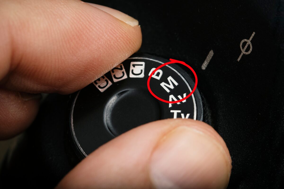 Auto Vs. Manual Mode: What Photographers Should Know A Person Is Holding A Button In Manual Mode With A Red Circle On It.