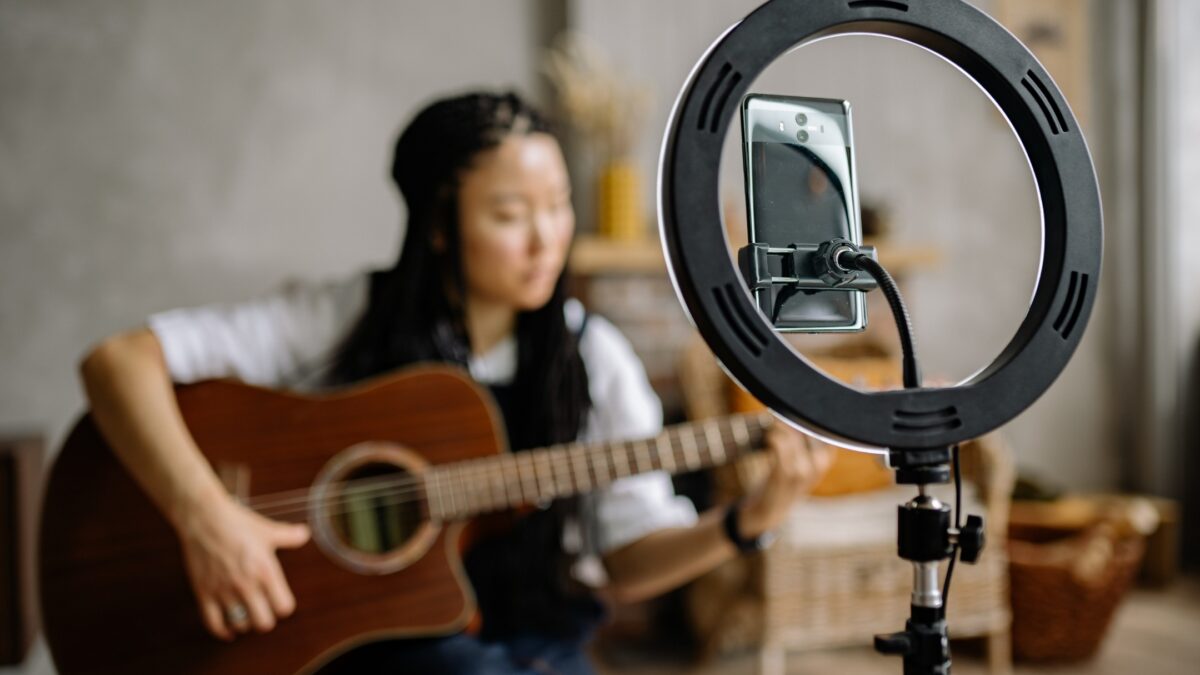 Photography Ring Light: 3 Best Choices For Content Creators A Woman Strumming An Acoustic Guitar While Illuminated By A Ring Light For Photography.