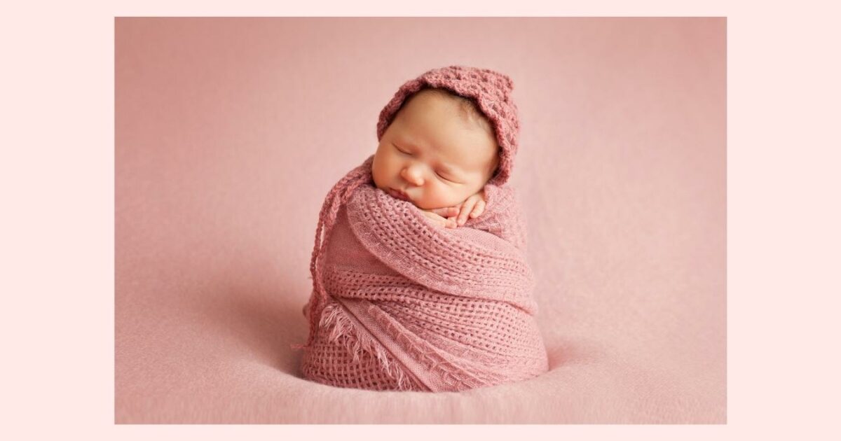 What To Wear To A Photoshoot (The Ultimate Guide) A Newborn Baby Wrapped In A Pink Blanket For A Photoshoot On A Pink Background.