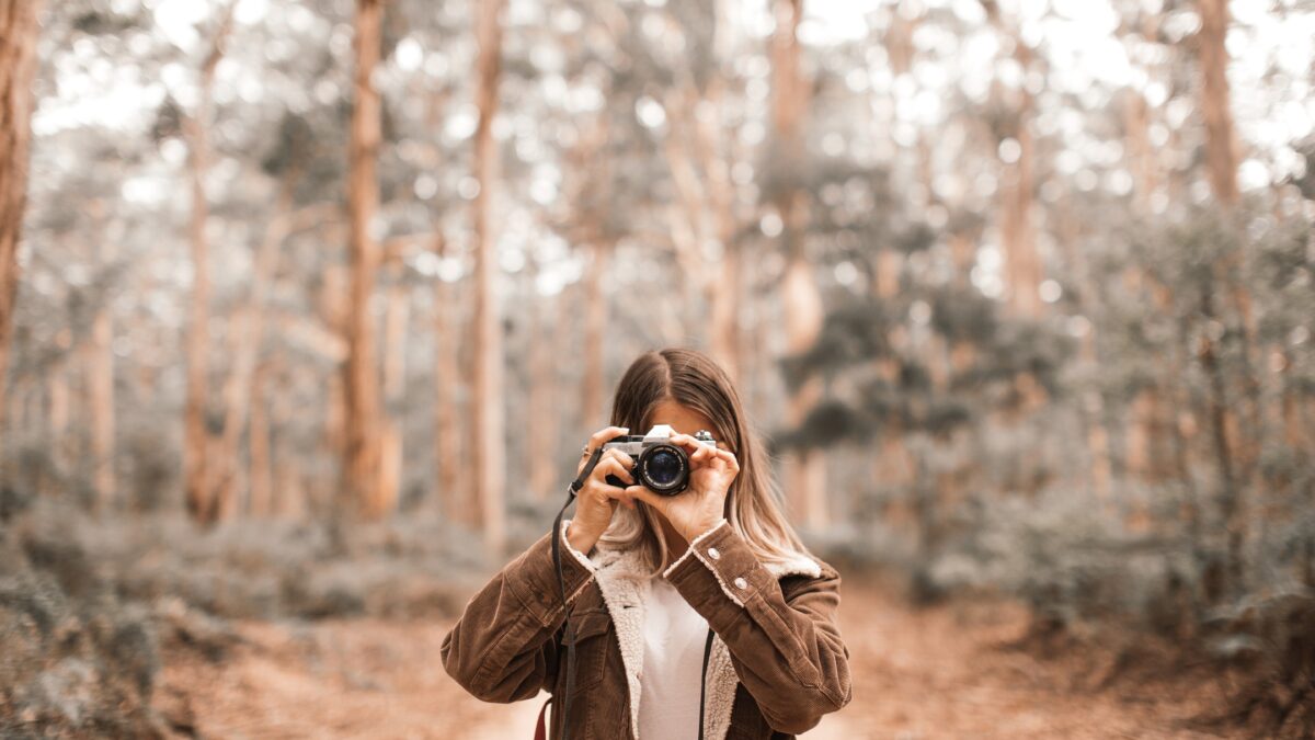 How To Learn And Improve From Mistakes As A Photographer A Woman, Making Mistakes As A Photographer, Captures A Picture With Her Camera In The Woods.