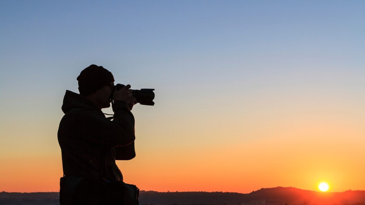 How To Build A Photography Portfolio As A New Photographer A Silhouette Of A Man Taking A Photo At Sunset.