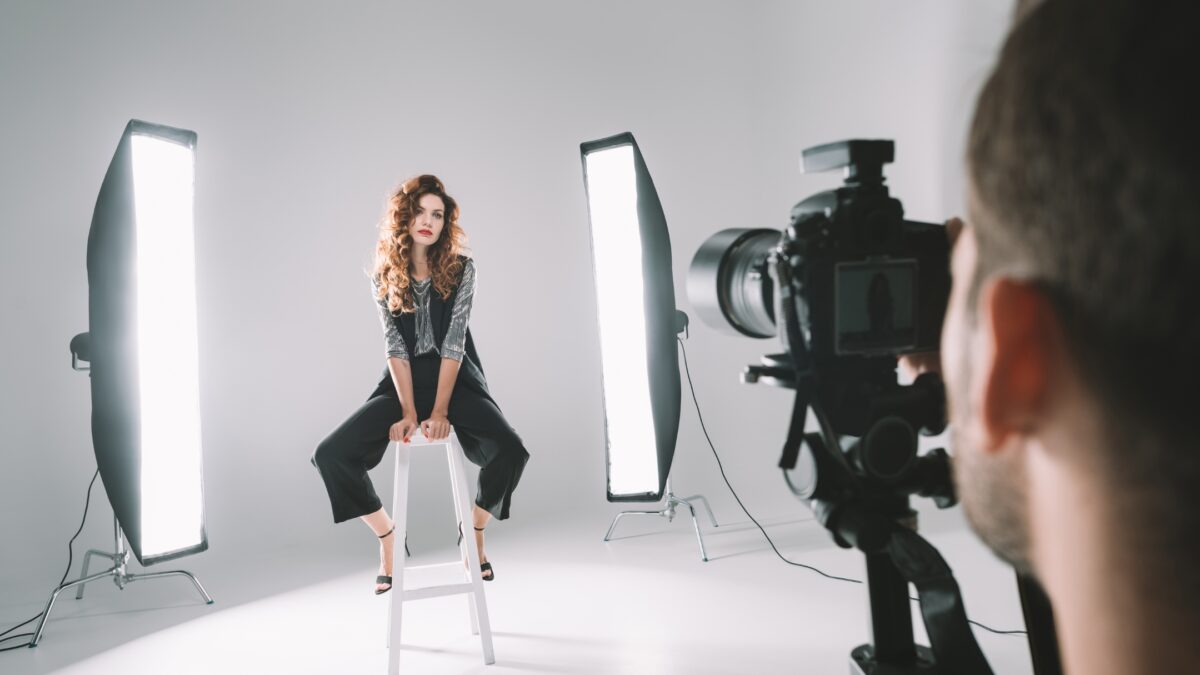How To Build A Photography Portfolio As A New Photographer A Woman Is Sitting On A Stool In Front Of A Camera.