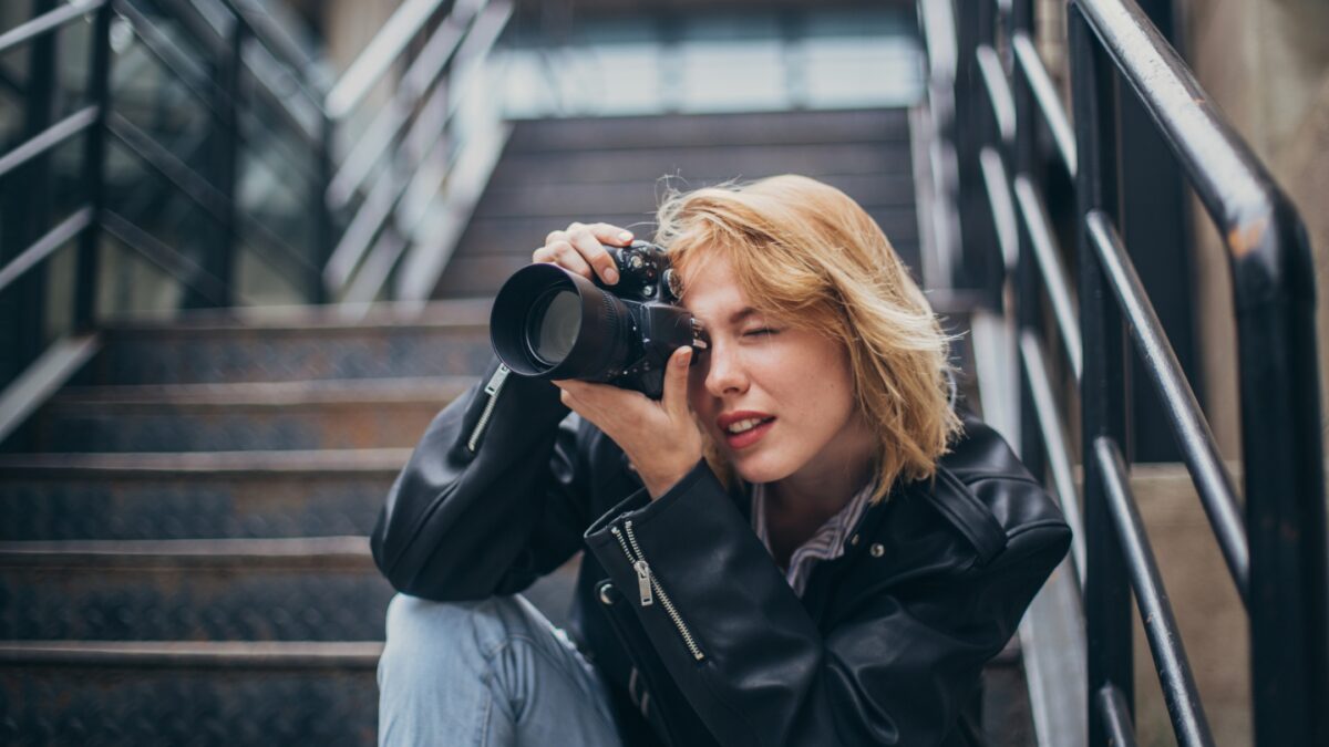 How To Build A Photography Portfolio As A New Photographer A Woman Taking A Picture With Her Camera On The Stairs.