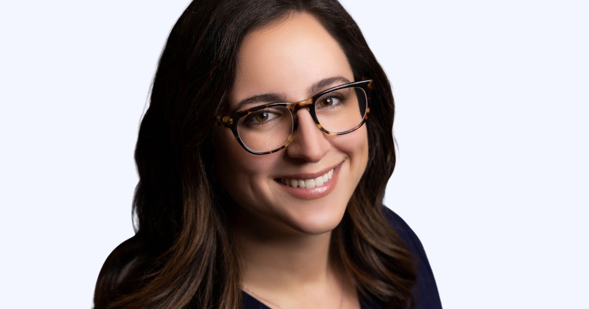 Photography For Beginners (How To Take Pictures Like A Pro) A Woman Wearing Glasses Smiles In Front Of A White Background, Captured In Photography.