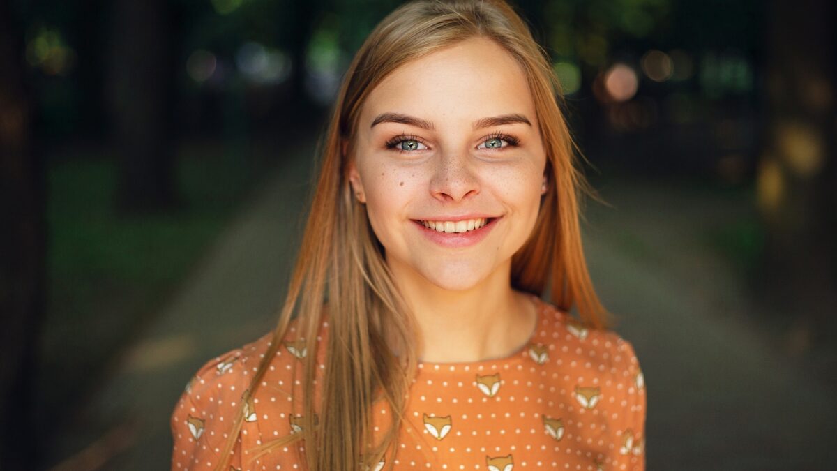 Photography Lighting Tips For Taking Better Photos A Young Woman Is Smiling In A Park While A Photography Lighting Setup Captures Her Joy.