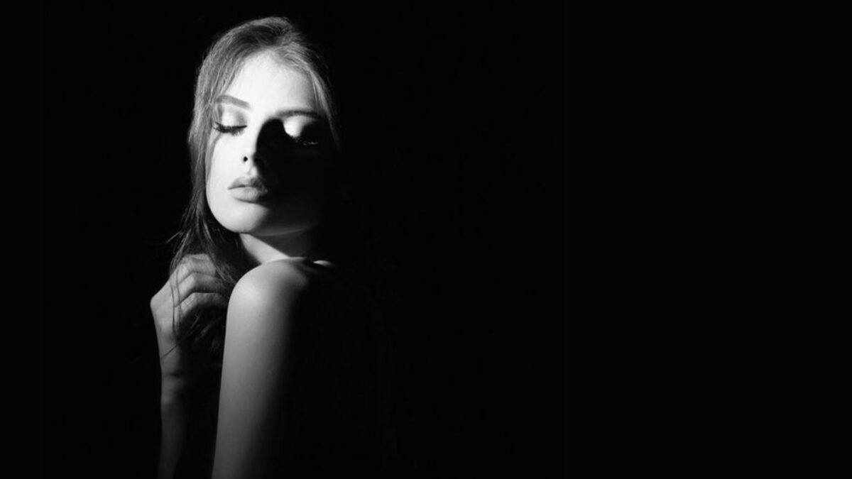 Shadow Photography (Tips And Secrets You Need To Know) A Black And White Photo Of A Woman Posing In The Dark, Showcasing Shadow Photography.
