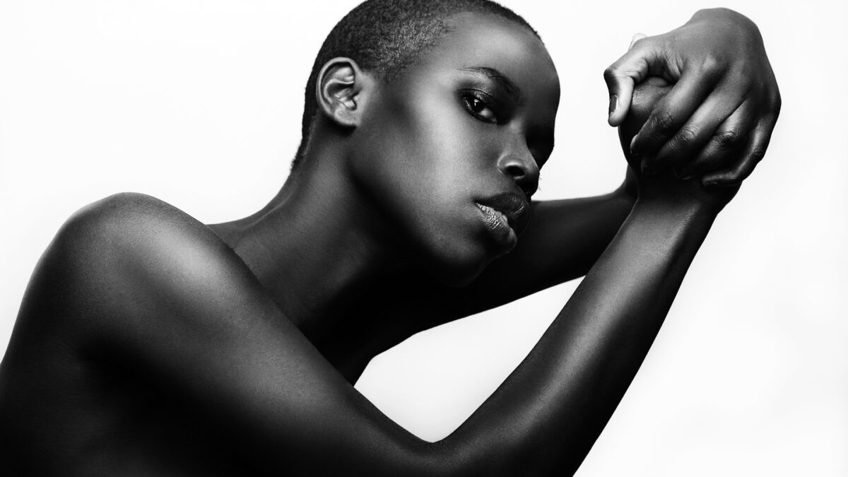 Photography Lighting Setup For Beginners (An Easy Guide) A Black Woman Is Posing In Front Of A White Background, Captured With A Photography Lighting Setup.