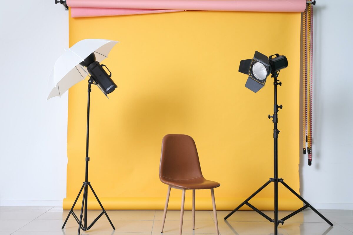12 Mistakes Photographers Make A Chair, Umbrella, And Lighting Equipment Set Up In Front Of A Yellow Backdrop.