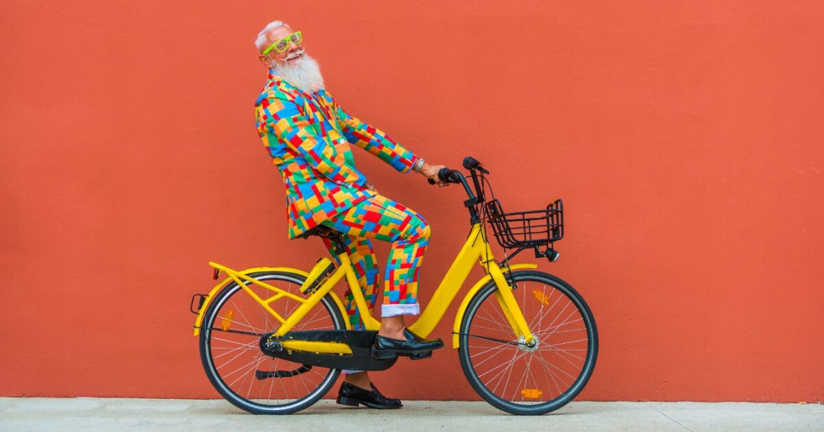 What To Wear To A Photoshoot (The Ultimate Guide) A Man Dressed In A Colorful Outfit Riding A Bicycle In A Photoshoot.