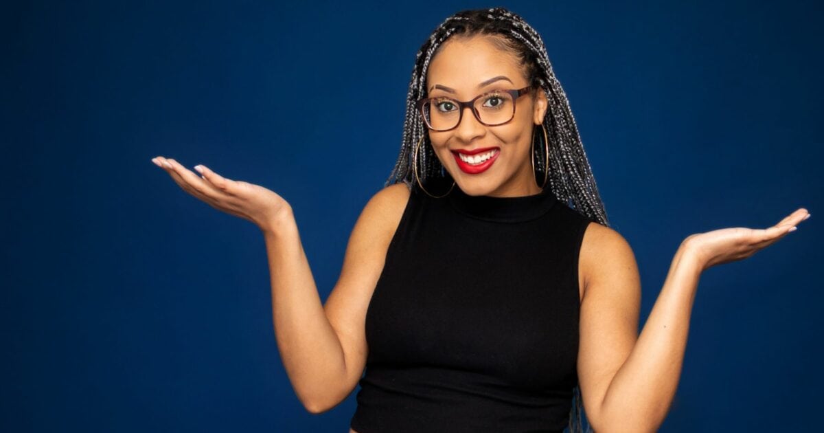 Best Photography Poses For Pictures (From A Pro Photographer) A Black Woman With Glasses Is Striking Photography Poses In Front Of A Blue Background.