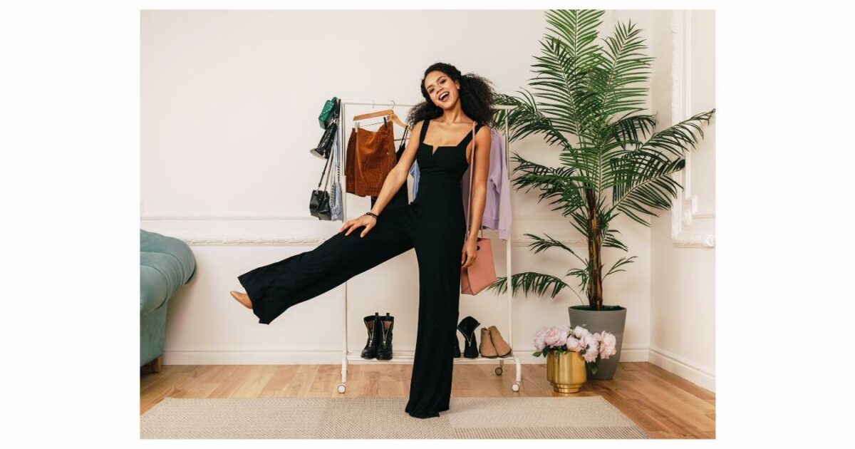 What To Wear To A Photoshoot (The Ultimate Guide) A Woman In A Black Jumpsuit Standing In Front Of A Rack, Showcasing An Ideal Outfit For A Photoshoot.