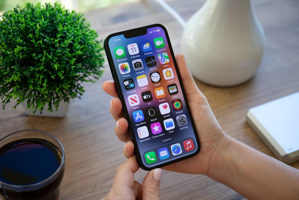 The History Of Photography (Timeline Included) A Person Using An Iphone X To Capture A Modern-Day Photograph Next To A Cup Of Coffee, Reflecting The Continued Evolution Of Photography.