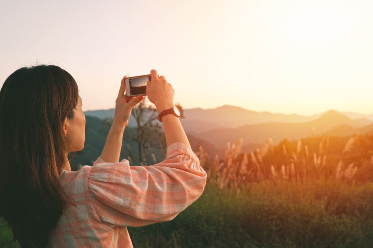 Mobile Photography Tips That'Ll Help You Take Better Photos A Woman Is Capturing A Stunning Mountain Vista With Her Cell Phone Using Mobile Photography Tips.