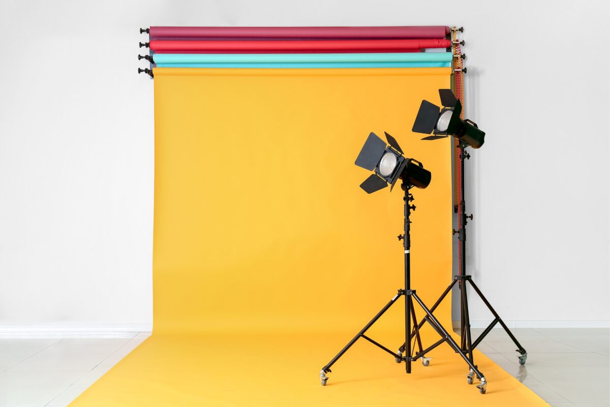 The Complete Guide To Photography Backdrops A Set Of Lights And A Photography Backdrop In Front Of A Yellow Background.